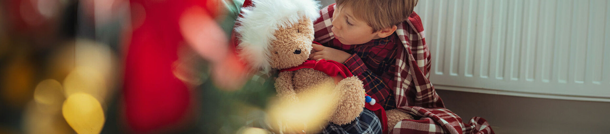 Kind mit Teddy vor einer Heizung