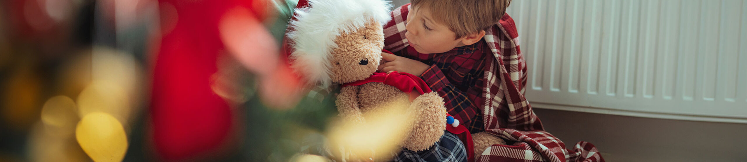 Kind mit Teddy vor einer Heizung